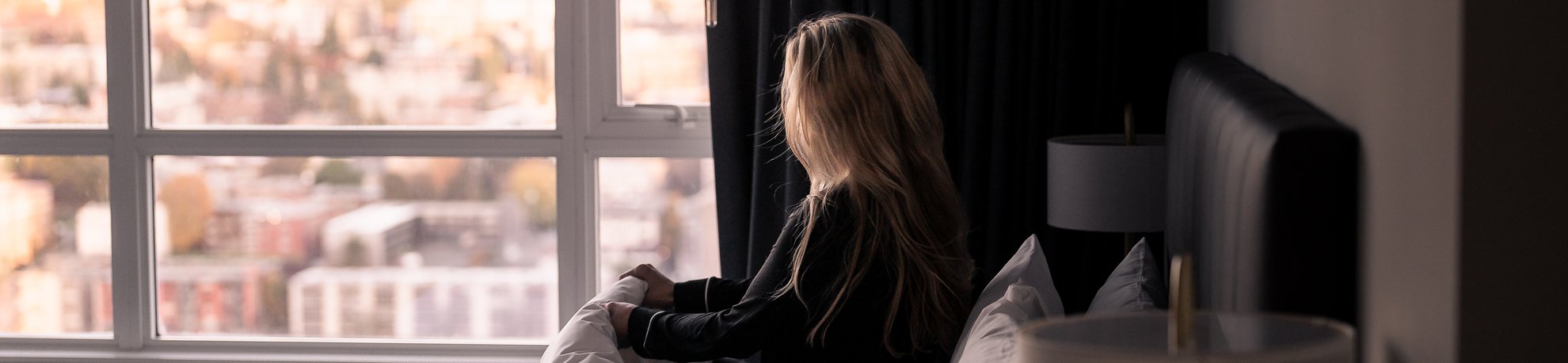 woman in sleep attire looking out the window of a suite at level seattle south lake union