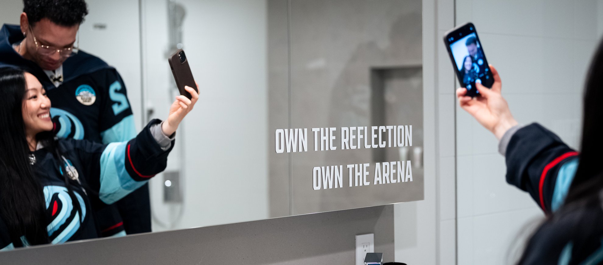 kraken fans taking a selfie in the bathroom of the kraken fan suite