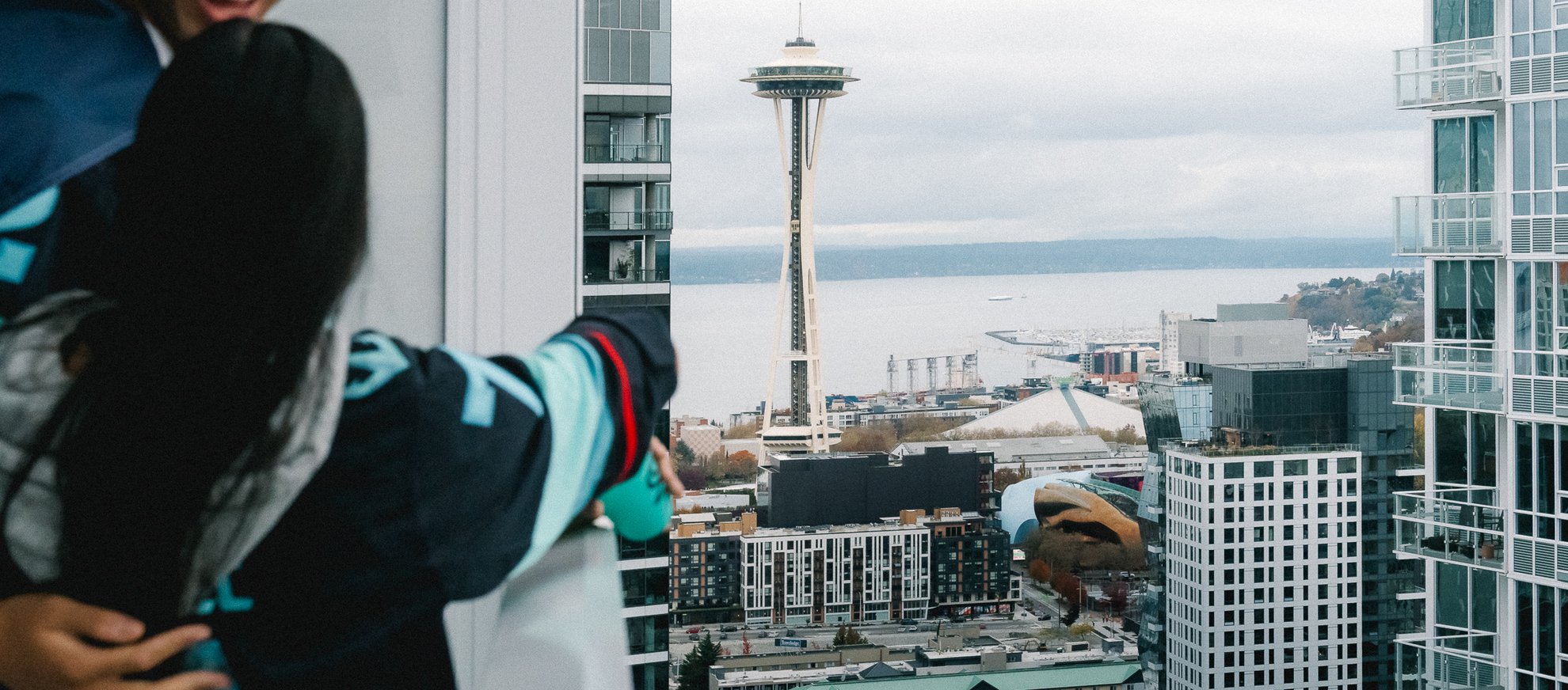 kraken fans pointing at the seattle space needle from the kraken fan suite balcony