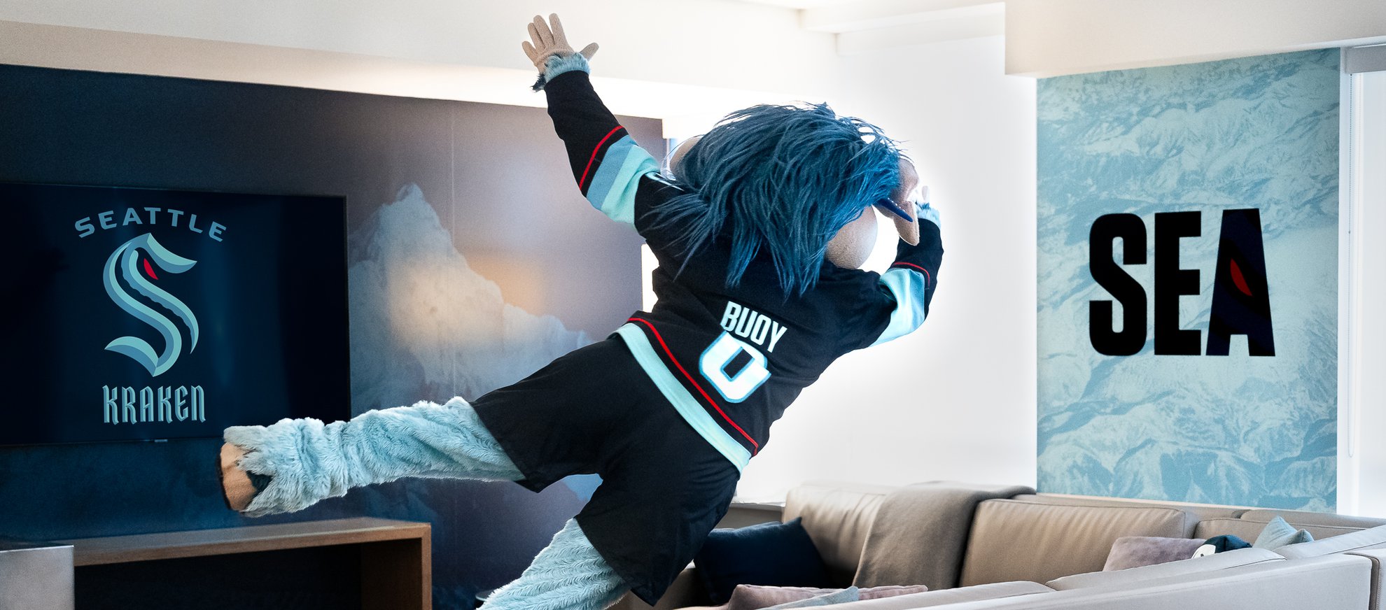 kraken mascot buoy jumping onto the couch in the kraken fan suite