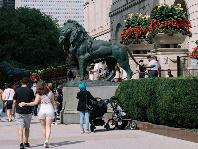 Couple walks in front of lion statue at Art institute of Chicago