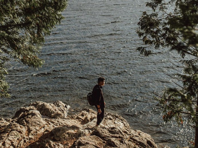 Man standing on rocks in front of Buntzen Lake in Port Moody