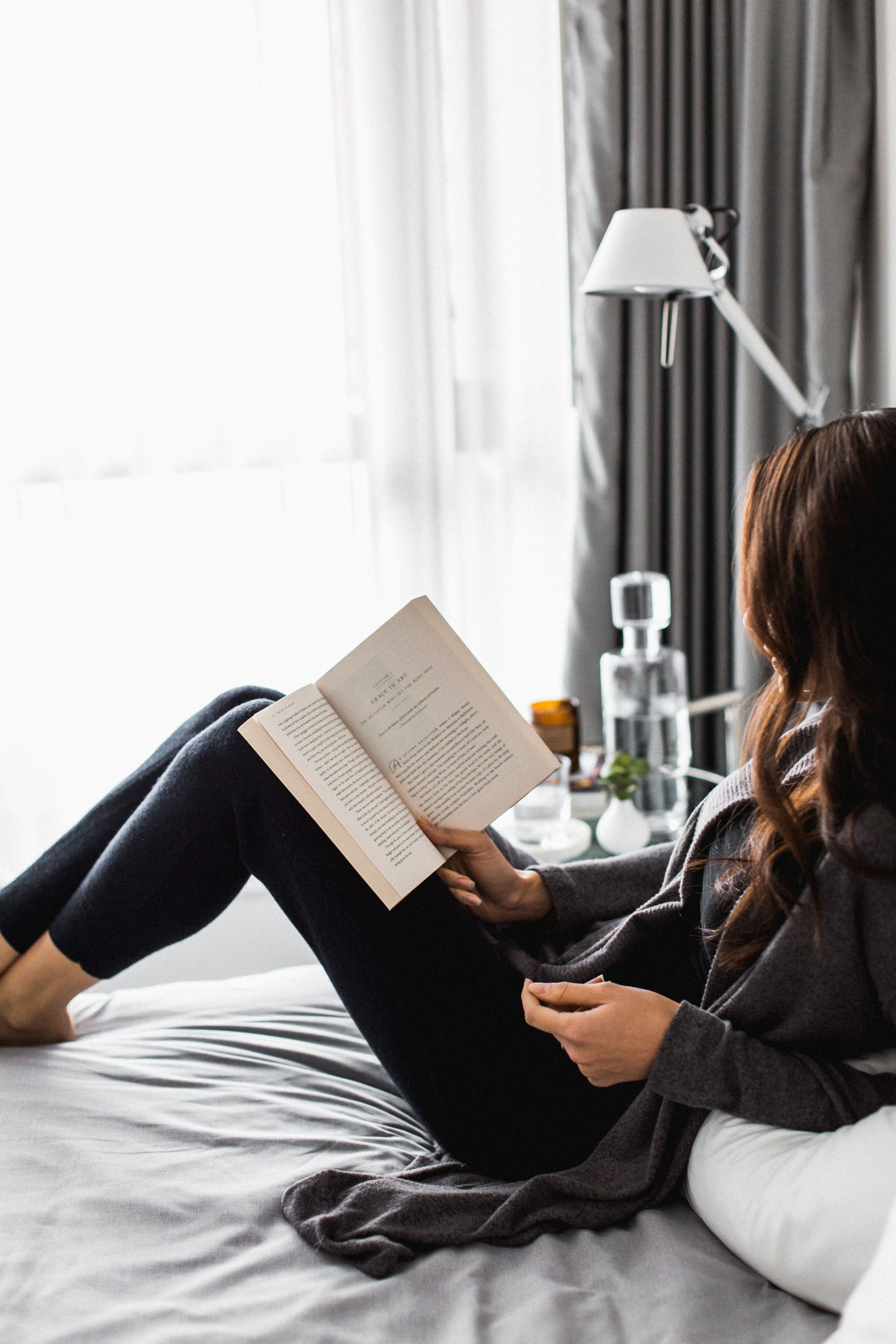 a girl reading book on the bed at level furnished suites in port moody