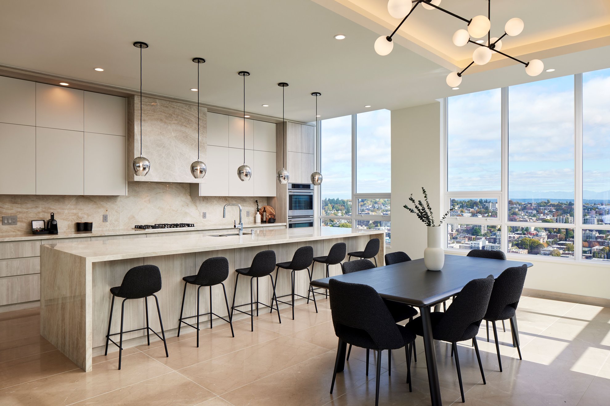 modern kitchen with marble counter island and black dining table with high ceilings and large window at level seattle.jpg