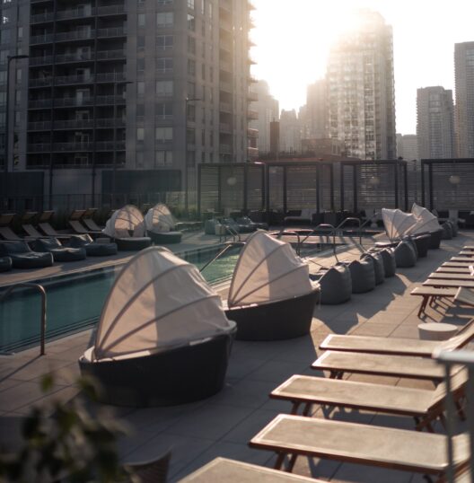 Rooftop pool area with lounge chairs and covered daybeds, empty at sunrise or sunset, surrounded by tall modern buildings—perfect for guests enjoying third night free hotel stays in Chicago, Los Angeles, and Seattle.
